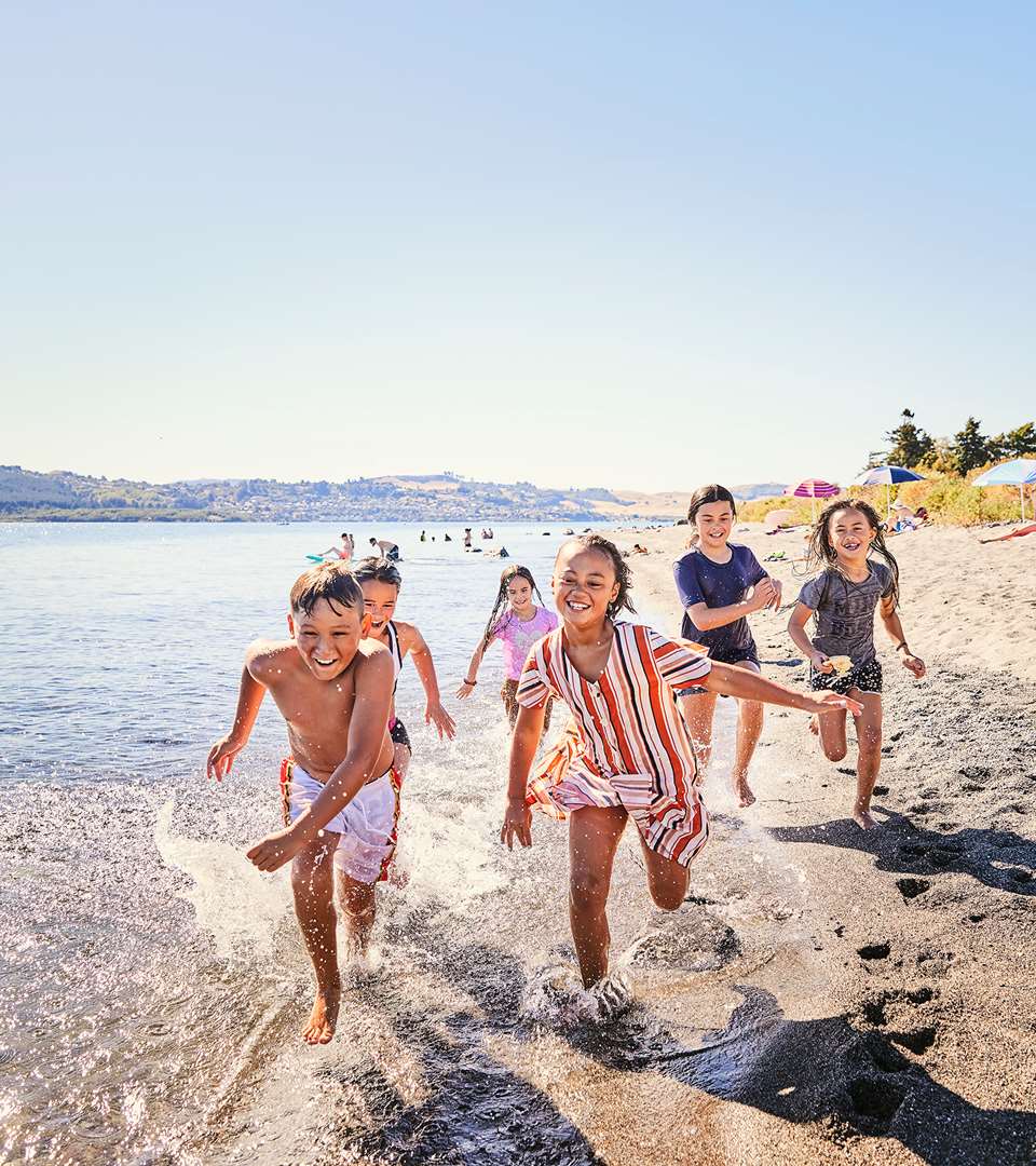 Lake Taupo Wharewaka - happy kids running on the beach - photo by Todd Eyre
