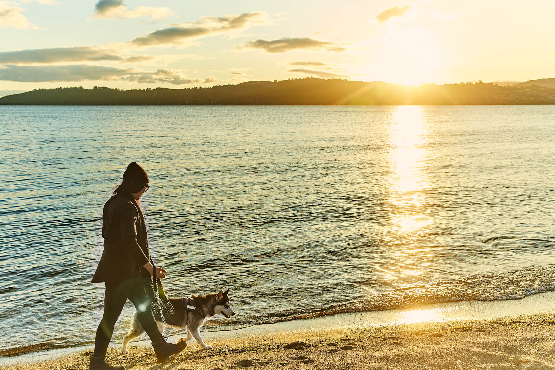 Woman walking her dog at Wharewaka, sunset Lake Taupo - By Todd Eyre